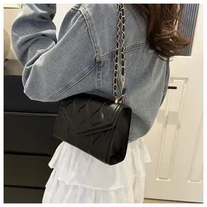 Close-up of black wave-quilted shoulder bag with golden chain strap for women