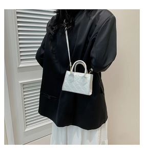 Detail shot of mini white quilted handbag with glossy finish and detachable shoulder strap