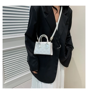 Detailed view of mini crossbody bag with diamond quilting and gold hardware on a model