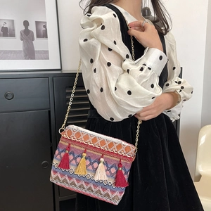 Ethnic knit crossbody bag with colorful patterns, tassels, and gold chain strap detail