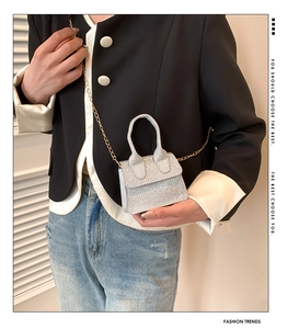 Crossbody view of mini silver sequin handbag with gold chain strap and top handle