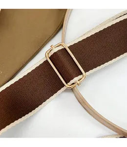 Close-up of adjustable woven shoulder strap with gold hardware on a brown saddle bag