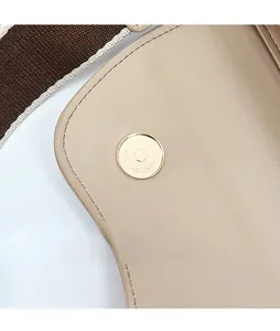 Detail of magnetic hardware buckle and beige leather texture on saddle shoulder bag