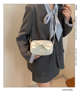 Détail du sac matelassé blanc crème avec un grand nœud décoratif et une bandoulière