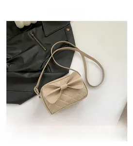 Détail d'un sac à bandoulière matelassé beige avec un grand nœud décoratif sur fond blanc