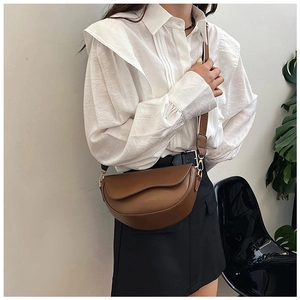 Detail shot of brown saddle bag in matte PU leather with wide fabric shoulder strap
