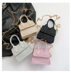 Detail view of four mini glitter handbags in pink, black, white, and silver with gold chains
