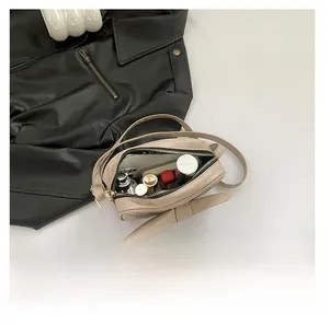 Détail de l'intérieur spacieux d'un sac bandoulière beige avec des objets du quotidien