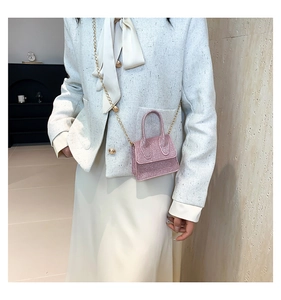 Close-up of pink glitter mini crossbody bag with golden chain strap on model