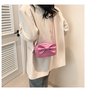 Vue détaillée d'un sac bandoulière matelassé rose avec un grand nœud sur un mannequin