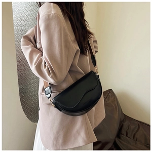 Detail of black matte saddle bag with wavy flap and adjustable wide fabric strap