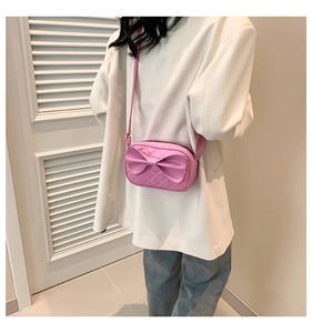 Détail du sac bandoulière rose en cuir PU avec nœud décoratif et texture matelassée