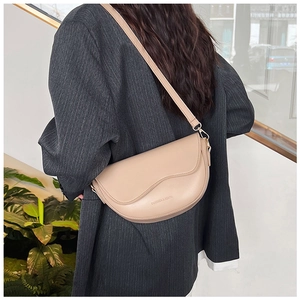 Side view of a beige matte leather saddle bag worn with a grey pinstripe suit