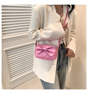 Détail du sac à bandoulière matelassé rose avec un grand nœud sur un blazer blanc