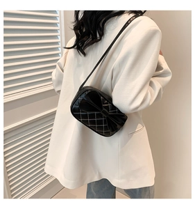 Détail d'un sac à bandoulière matelassé noir avec nœud sur un blazer blanc chic