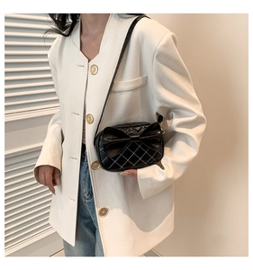 Détail d'un sac à bandoulière matelassé noir avec un grand nœud et coutures blanches