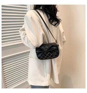 Détail du sac bandoulière matelassé noir avec grand nœud et texture en cuir PU lisse