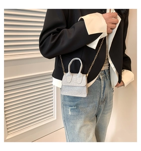 Macro view of silver glitter mini handbag with elegant gold chain strap detail