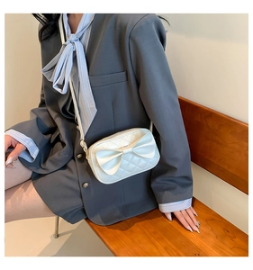 Détail du sac bandoulière blanc matelassé avec grand nœud et texture en cuir