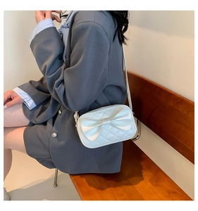 Vue détaillée d'un sac bandoulière blanc à nœud et texture matelassée sur modèle