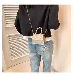 Mini gold glitter crossbody bag shown on waist highlighting the compact chain strap design