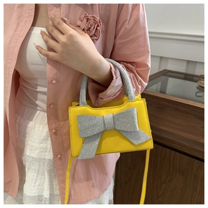 Detail der modischen gelben Handtasche mit großer silberner Schleife und Crossbody-Riemen