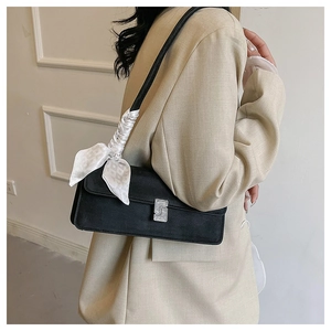 Detail of black underarm bag with silver rhinestone buckle and white silk scarf handle