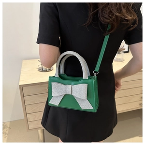 Detailansicht der grünen Handtasche mit großer glitzernder silberner Schleife und Riemen