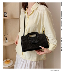 Close-up of black crocodile pattern handbag with square hollow handle and thin strap