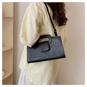 Black faux leather shoulder bag with crocodile pattern texture shown on a female model