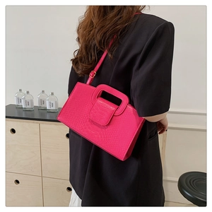 Fashionable rose pink crocodile pattern handbag worn with black blazer for women