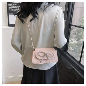 Details einer rosa Umhängetasche mit Strass-Schleife und eleganter Metall-Kettenriemen