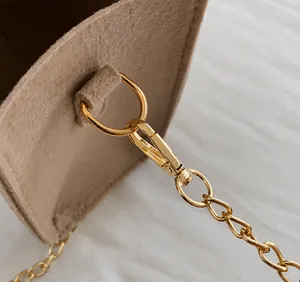 Close-up of premium gold lobster clasp and chain attached to a brown felt shoulder bag