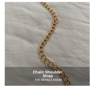 Detail shot of a glossy gold metal chain shoulder strap on textured fabric background