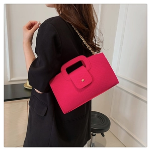 Detail view of pink crocodile embossed handbag with gold chain on model's shoulder