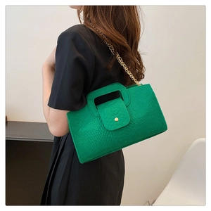 Detail of bright green crocodile pattern handbag with gold chain strap and metal buckle