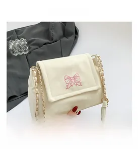 Close-up of embroidered butterfly on cream white faux leather bag with gold chain strap