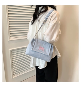 Detailed close-up of pink butterfly embroidery on light blue chain shoulder bag
