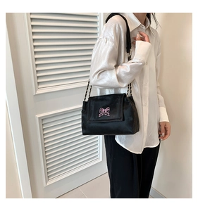 Detail of black velvet crossbody bag with pink butterfly embroidery and gold chain strap