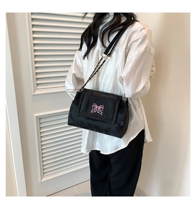 Close-up of black velvet shoulder bag with pink butterfly embroidery and chain strap