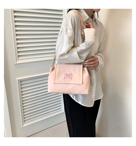 Close-up of pink shoulder bag featuring butterfly embroidery and metal chain strap