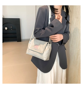 Detail of silver grey crossbody bag featuring pink butterfly embroidery and chain strap