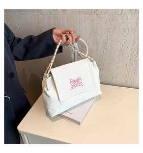 Close-up of pink butterfly embroidery and gold chain strap on a white leather shoulder bag