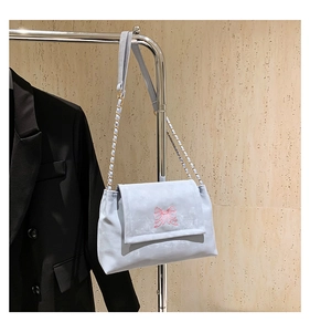 Detail of blue-grey crossbody bag with pink butterfly embroidery on metal hanger