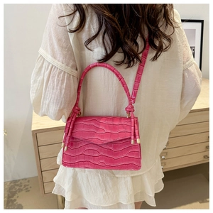 Pink croc-embossed crossbody bag with gold hardware shown on model in home setting