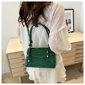 Detail of dark green faux crocodile leather crossbody bag on white dress outfit