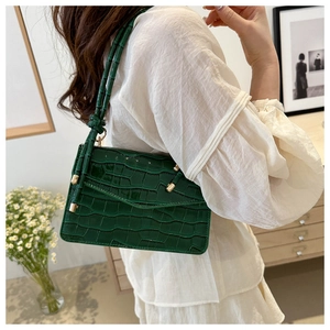 Detail of dark green crocodile texture handbag with gold buckle on a model