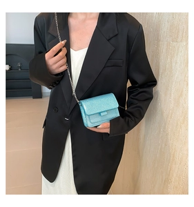 Détail d'un sac bandoulière pailleté bleu clair avec chaîne argentée porté par un mannequin