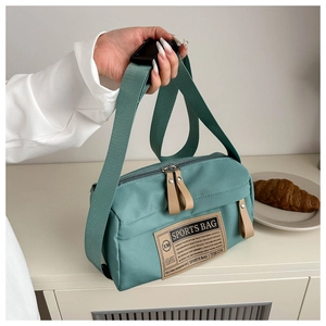 Détail du sac bandoulière en nylon vert avec double fermeture éclair et écusson cuir