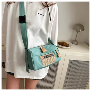 Détail du sac bandoulière vert menthe en tissu oxford avec sangle réglable et tirettes cuir